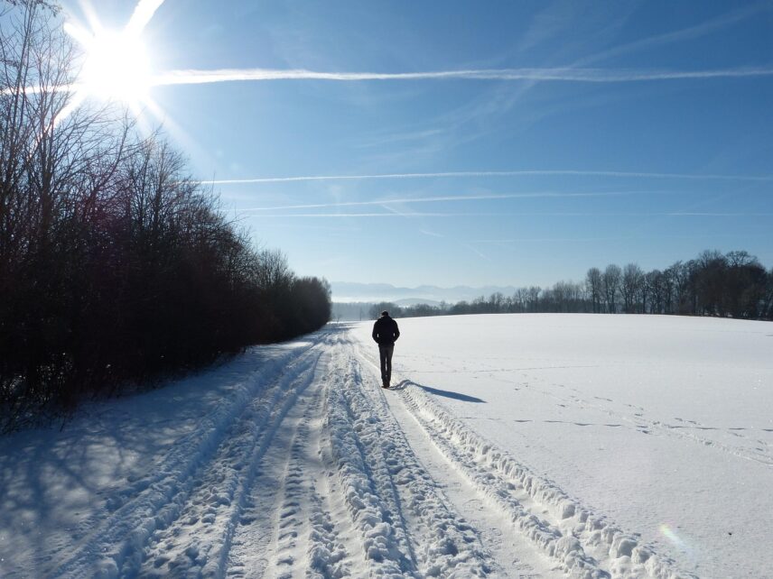 A man walks through the snow, illuminated by the bright winter sun Snow